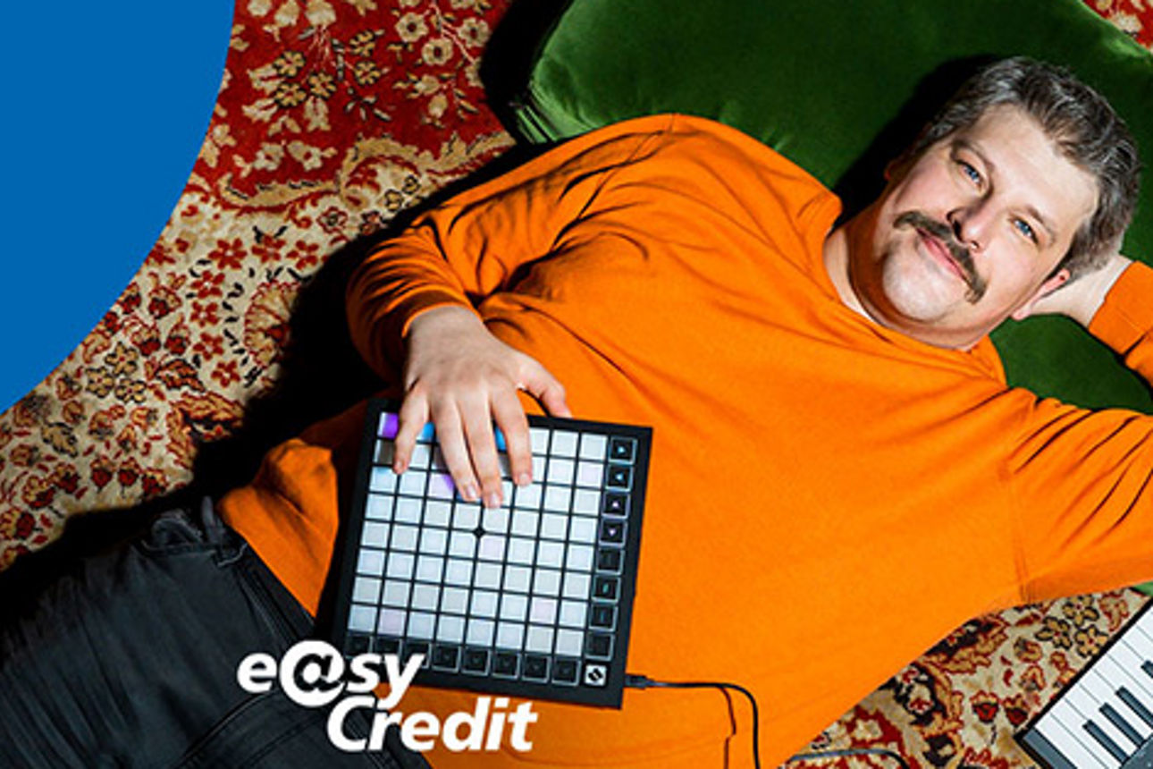 Mann mit Keyboad auf Rücken liegend, Blick in die Kamera