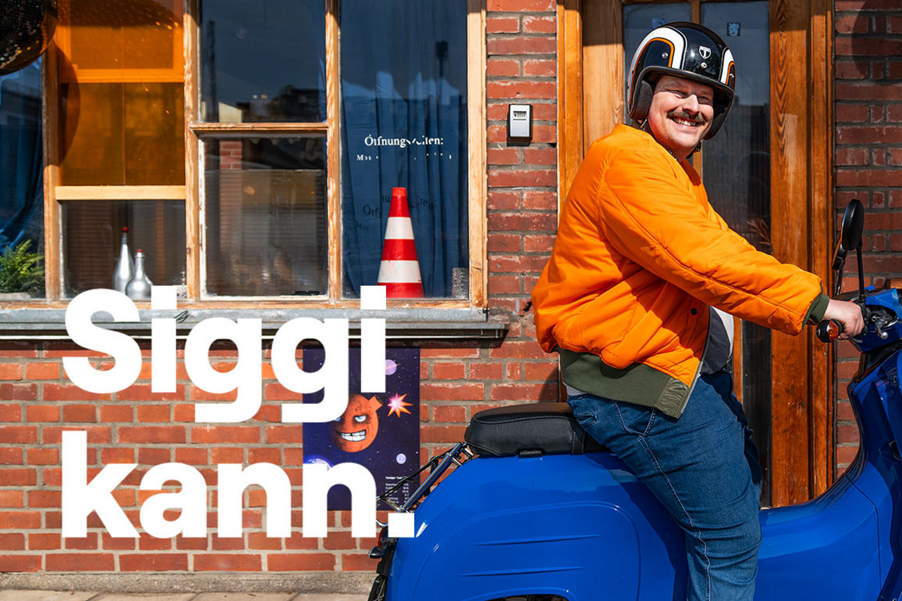 Mann mit Helm und orangefarbener Jacke sitzt auf einem blauen Moped und lächelt in die Kamera