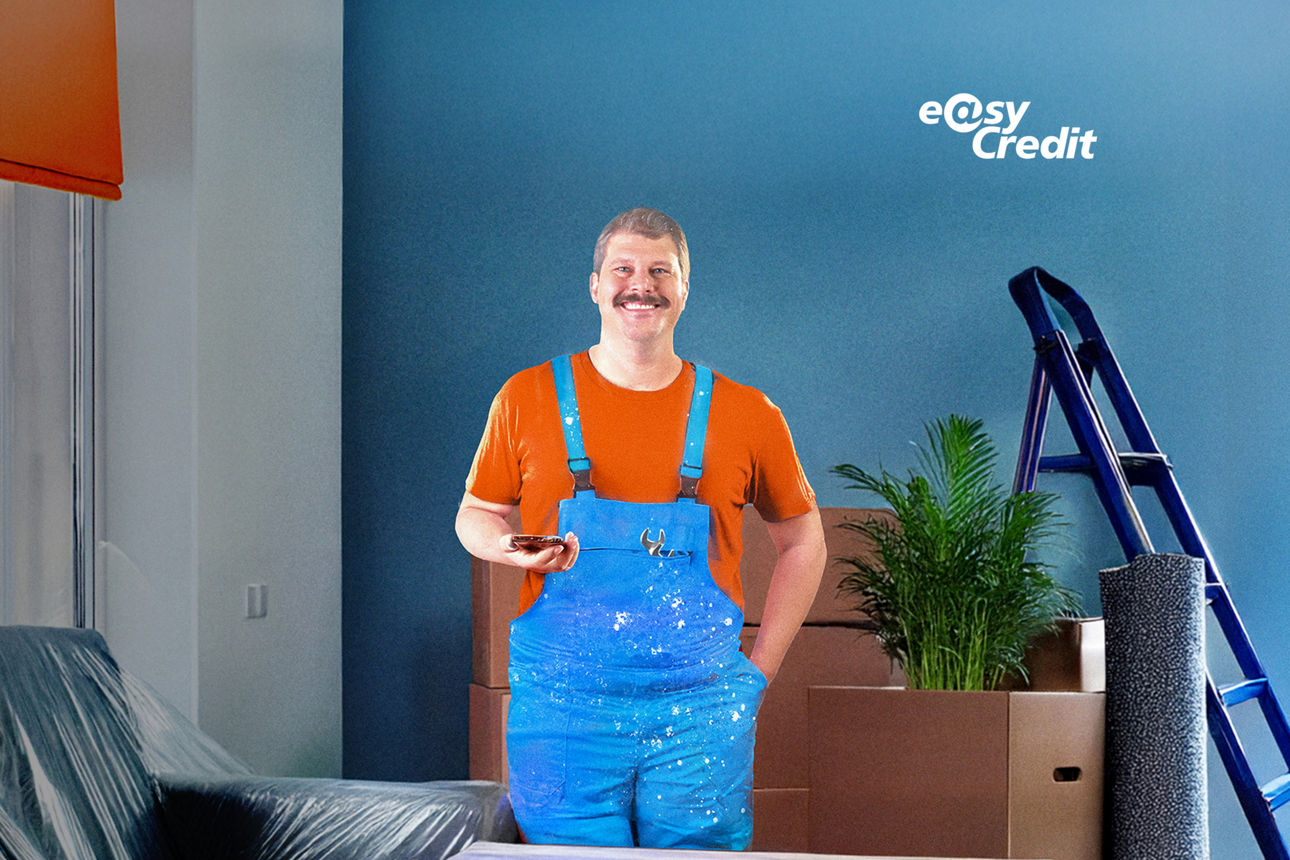 Mann steht in Latzhose vor einer blauen Wand