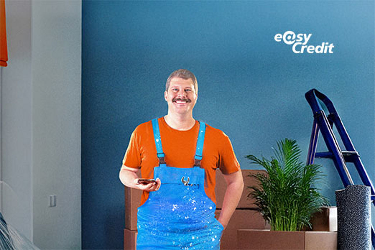 Mann in Latzhose steht in einem Zimmer zur Renovierung. Logo von easyCredit