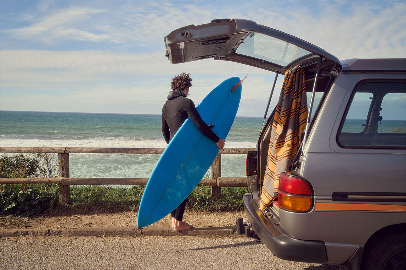 Mann mit Surfbrett am Van – Sofortkredit mit finanziellem Spielraum für spontane Pläne und Reisen