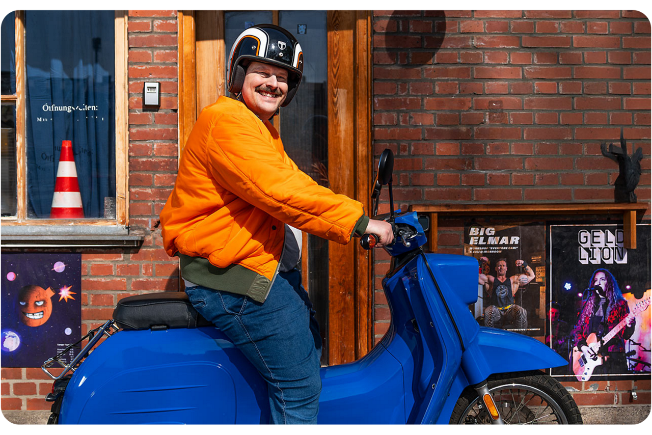 Mann auf einem blauen Moped