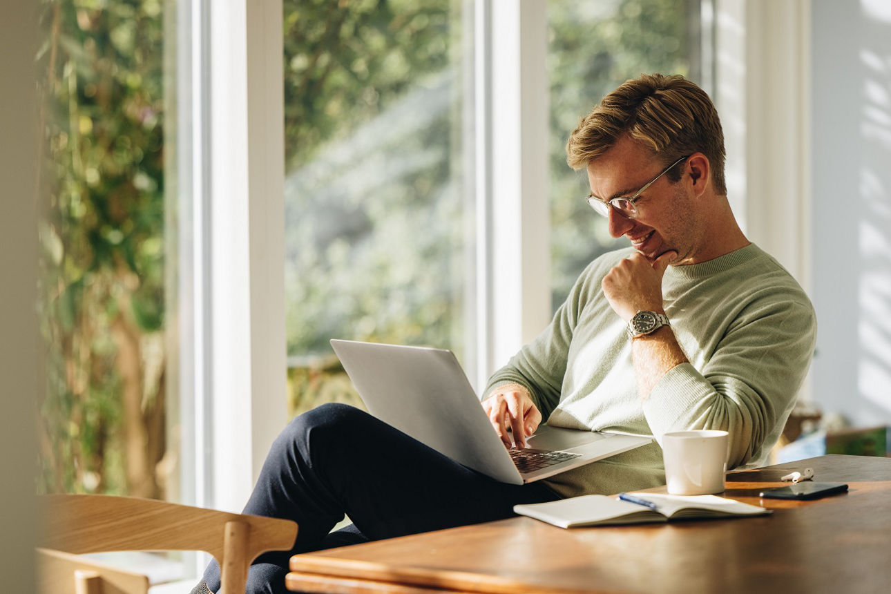 Frau sitzt in einem Sessel und schaut auf ein Laptop
