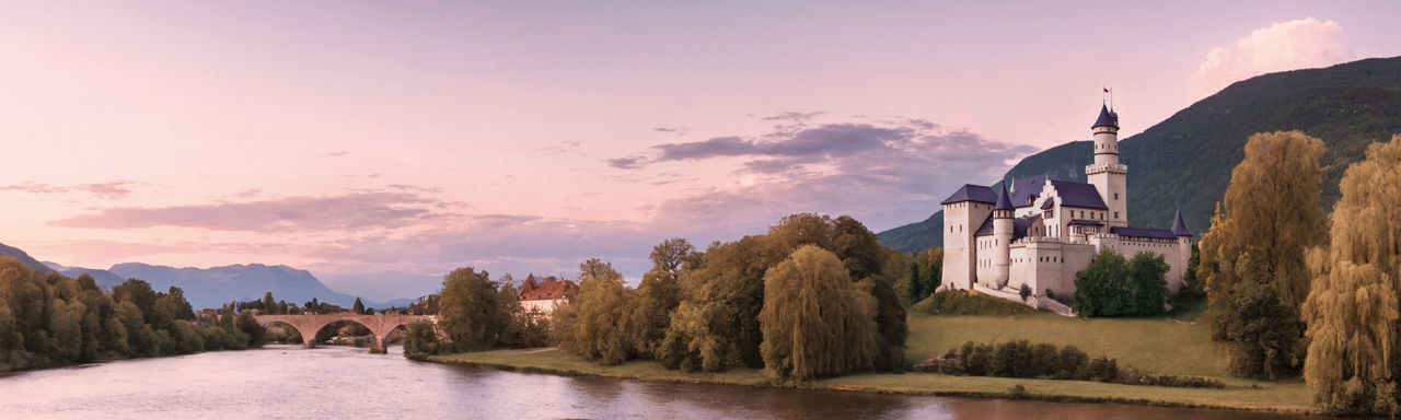 Weißes Schloss am See vor einer Bergkette