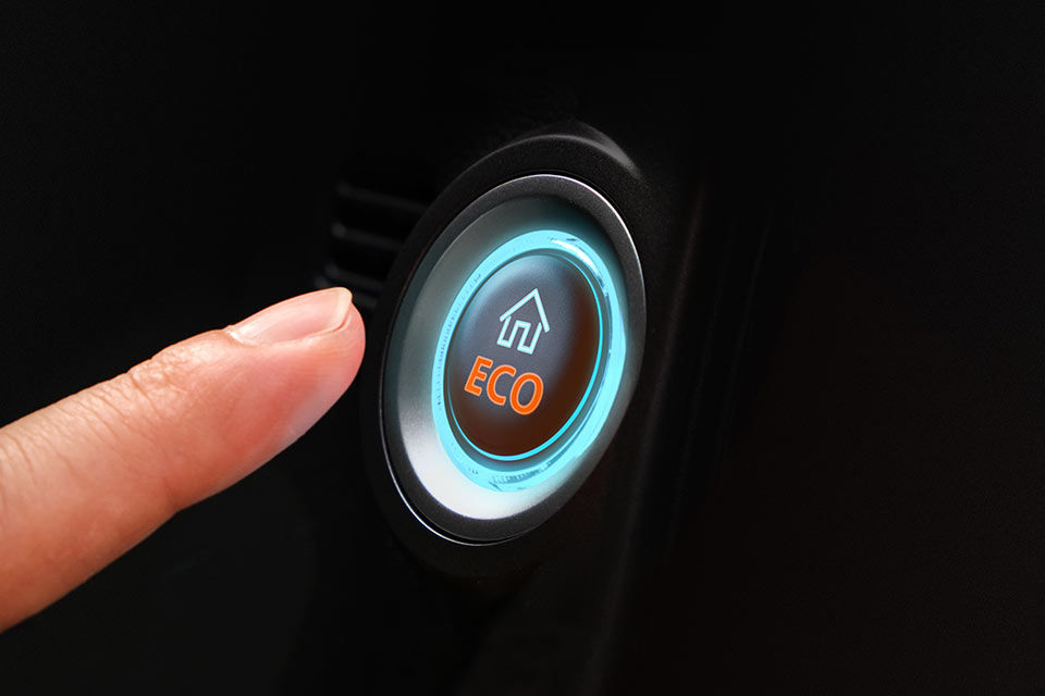 Finger, der auf einen Starknopf „Eco” drückt