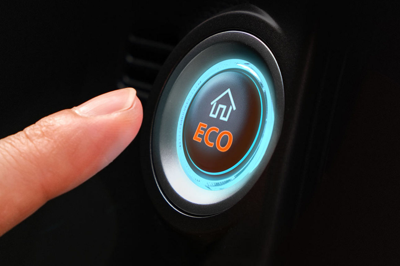 Finger, der auf einen Starknopf „Eco” drückt