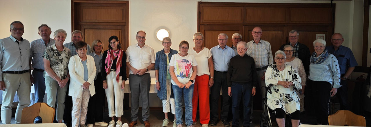 Viele Menschen in einem Raum mit Holzwänden, die für die Kamera posieren