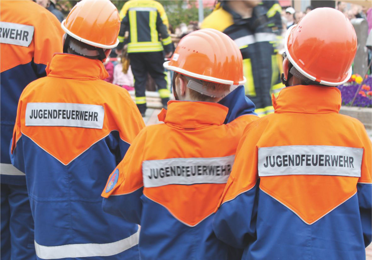 drei junge Leute in orange-blauen Jacken