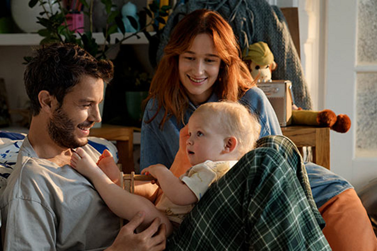 Ein junges Paar mit einem Baby schaut sich liebevoll an