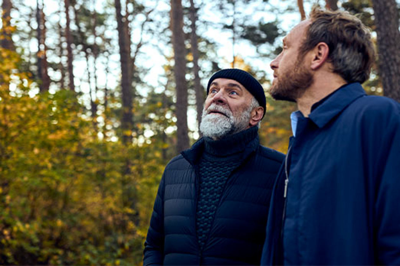 Ein älterer und ein jüngerer Mann im Wald