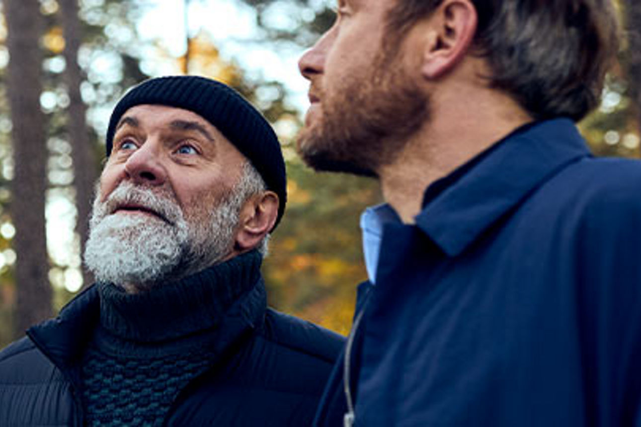 zwei Menschen im Wald, die sich in den Himmel strecken