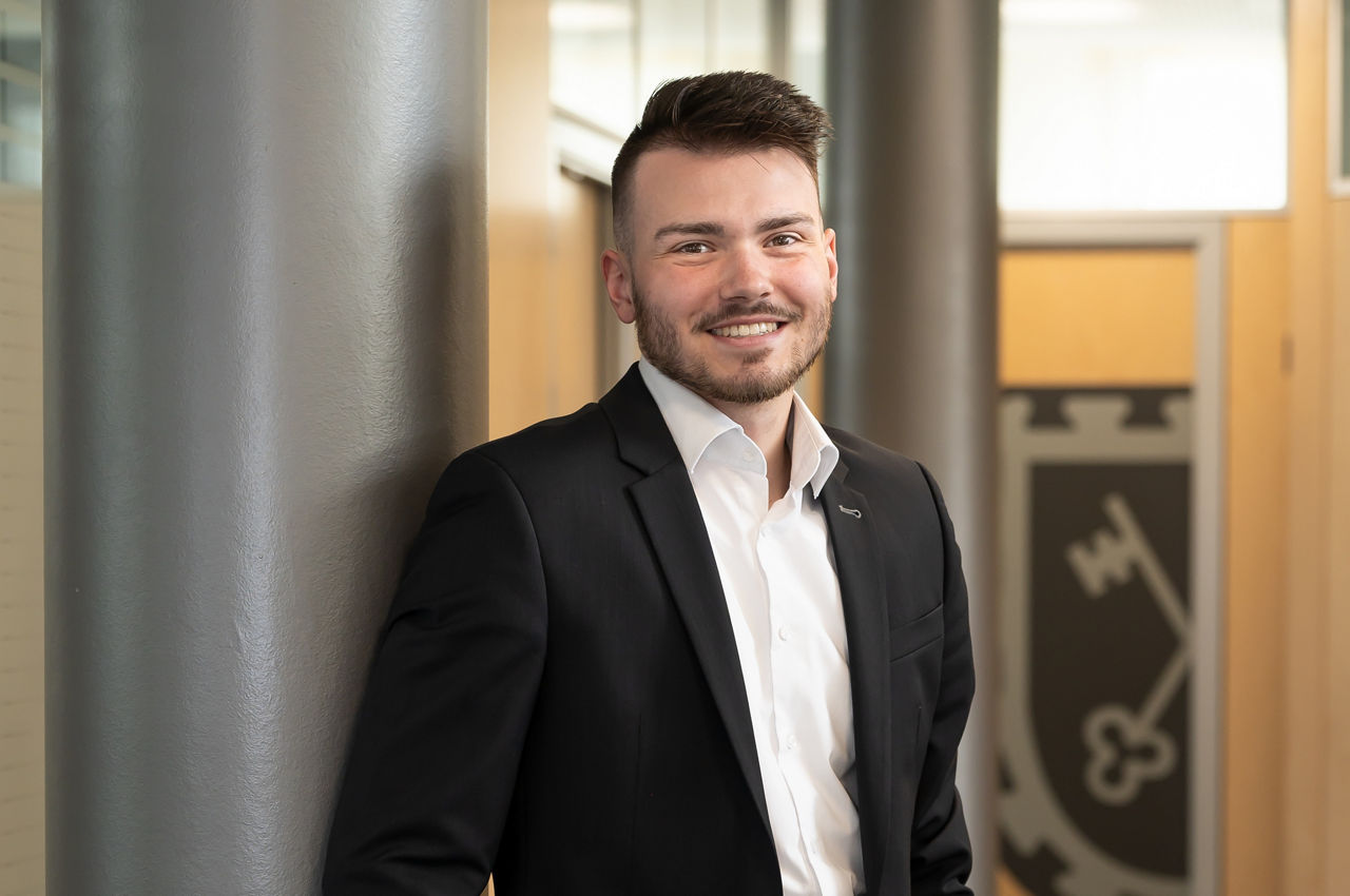 Mann sitzt lächelnd am Schreibtisch in der Bank