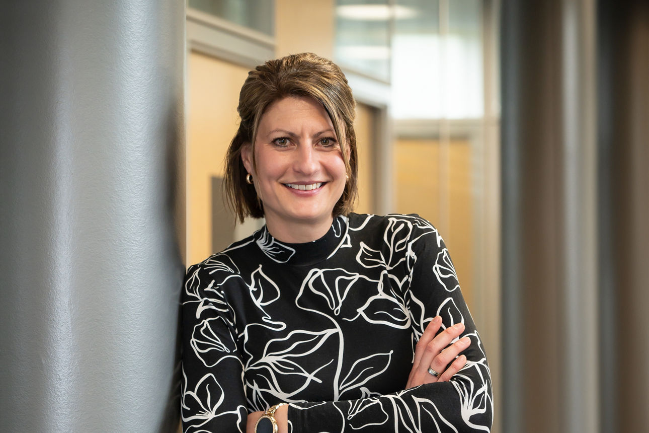 Eine Frau mit Headset sitzt lächelnd an ihrem Arbeitsplatz