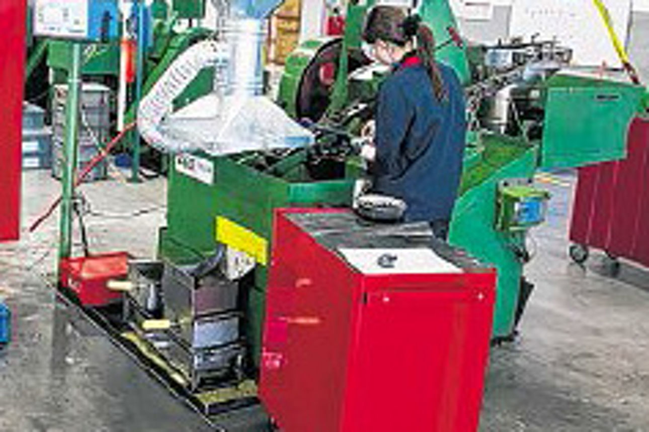 Eine Frau in Arbeitskleidung arbeitet an einer grünen Maschine in einer Fabrik