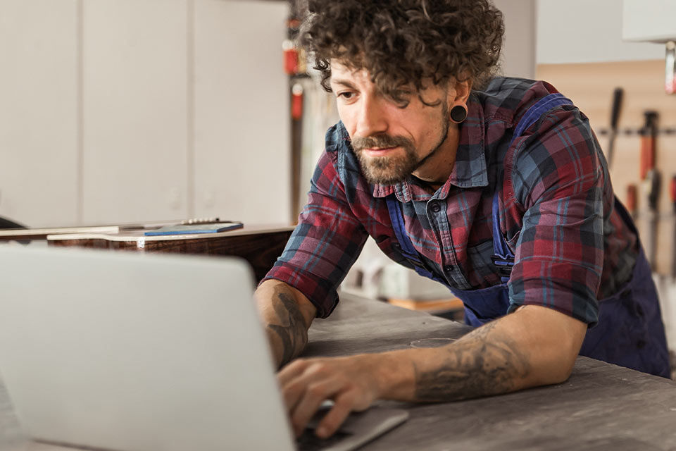 Ein junger Mann arbeitet auf seiner Werkbank an seinem Notebook