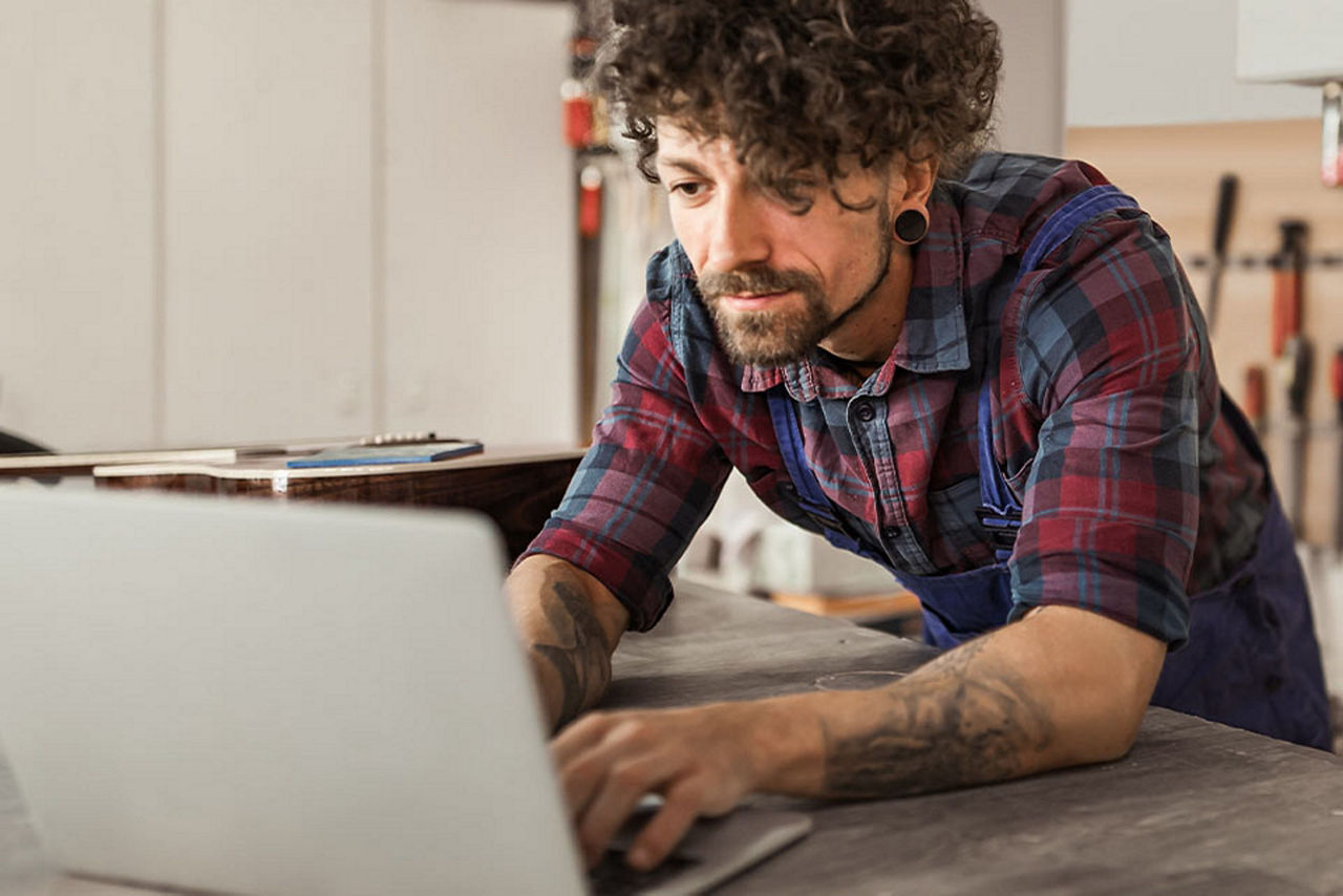 Ein junger Mann arbeitet auf seiner Werkbank an seinem Notebook