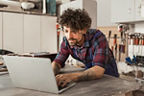 Ein junger Mann arbeitet auf seiner Werkbank an seinem Notebook