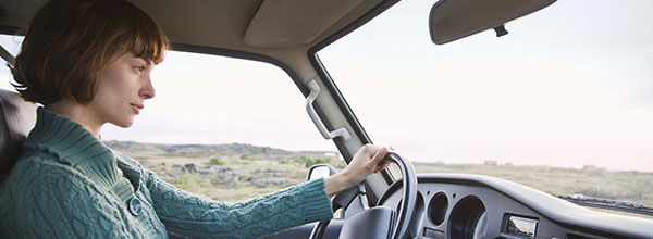 Eine Frau mit kurzen, braunen Haaren fährt ein Auto.