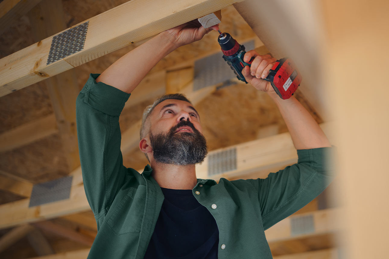 Mann befestigt Holzlatten an einer Decke