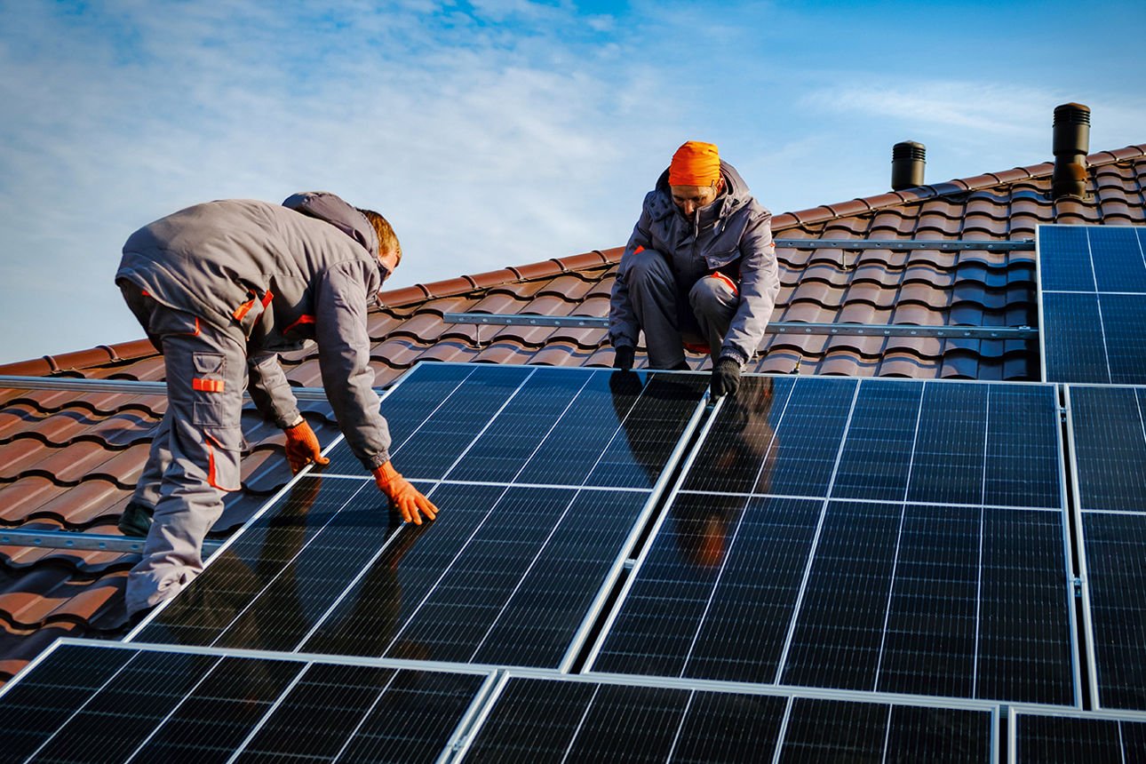 Handwerker installieren Solarpanele auf einem Dach