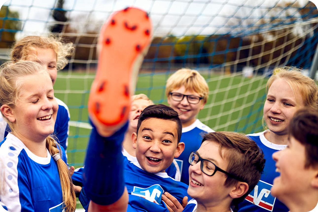 Eine Kinder-Fußballmannschaft in Volksbank-Trikots feiert einen Torschützen
