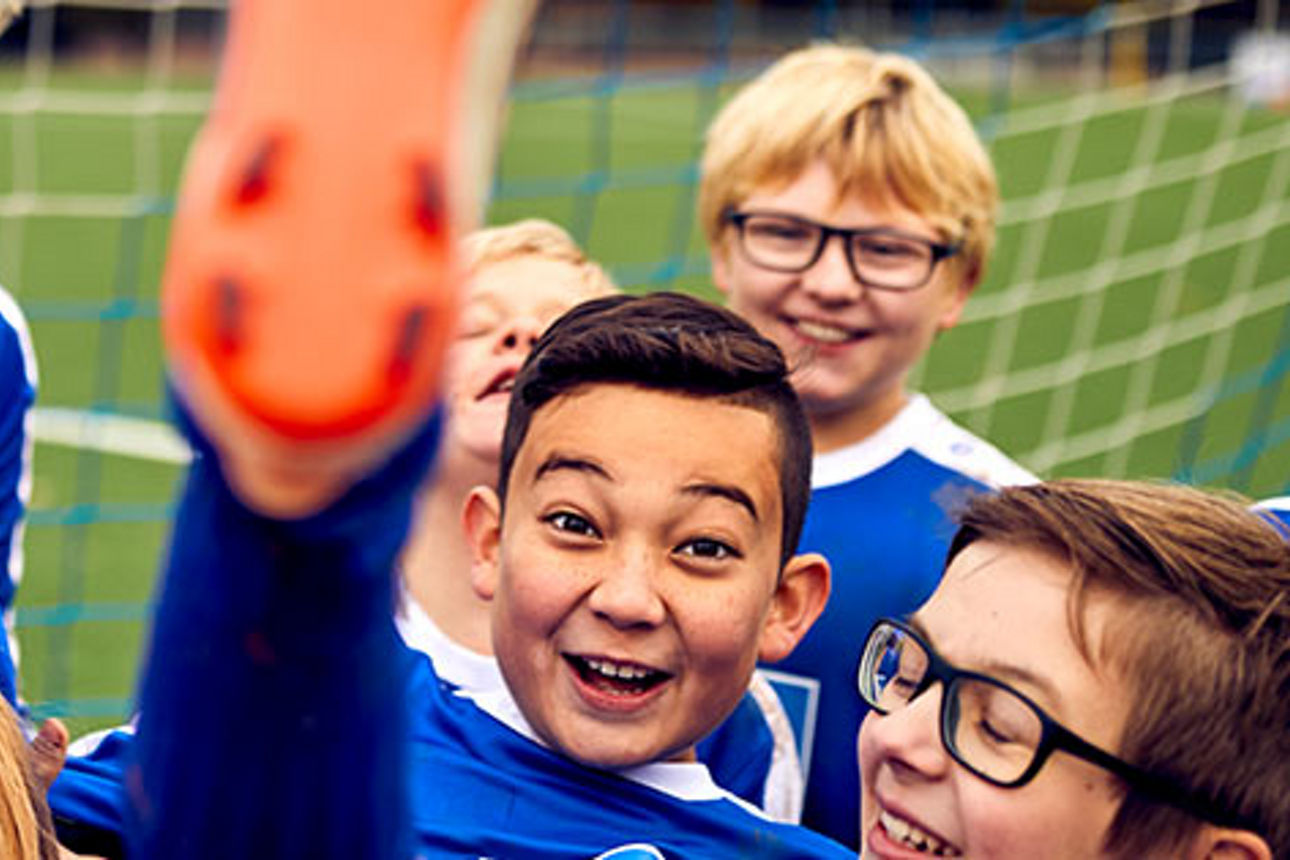 Jungs und Mädchen einer Fussballmannschaft lachen und freuen sich