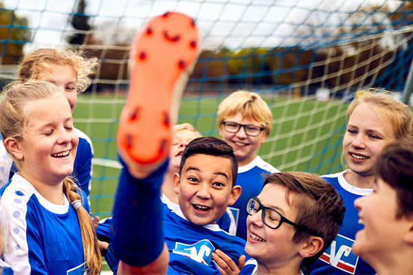 Kinder-Fußballmannschaft in Volksbanktrikots feiert einen Torschützen