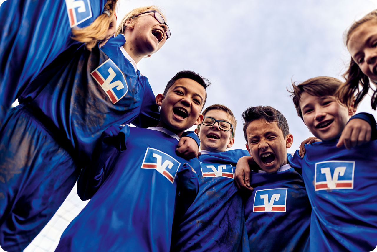 Fußballkinder liegen sich in den Armen und lachen