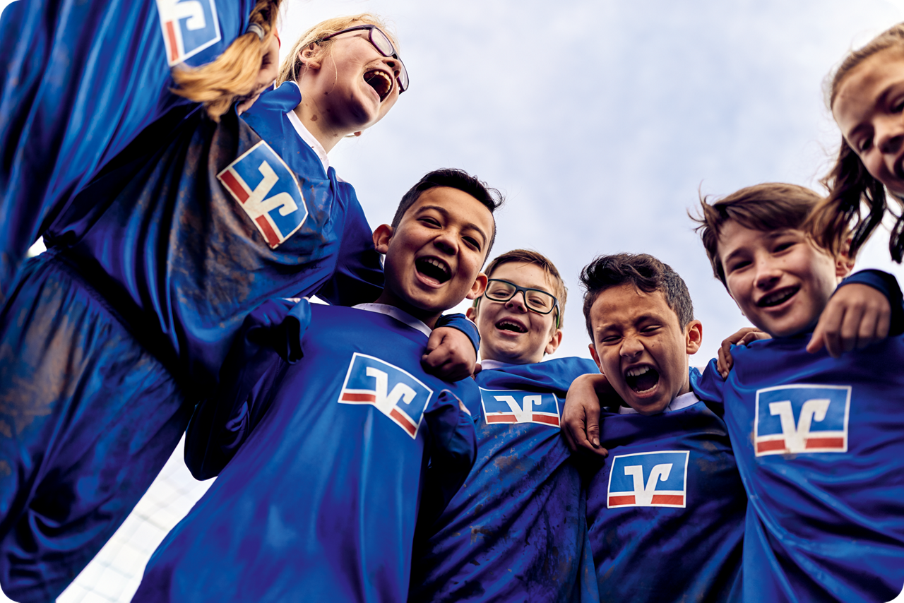 Fußballkinder liegen sich in den Armen und lachen