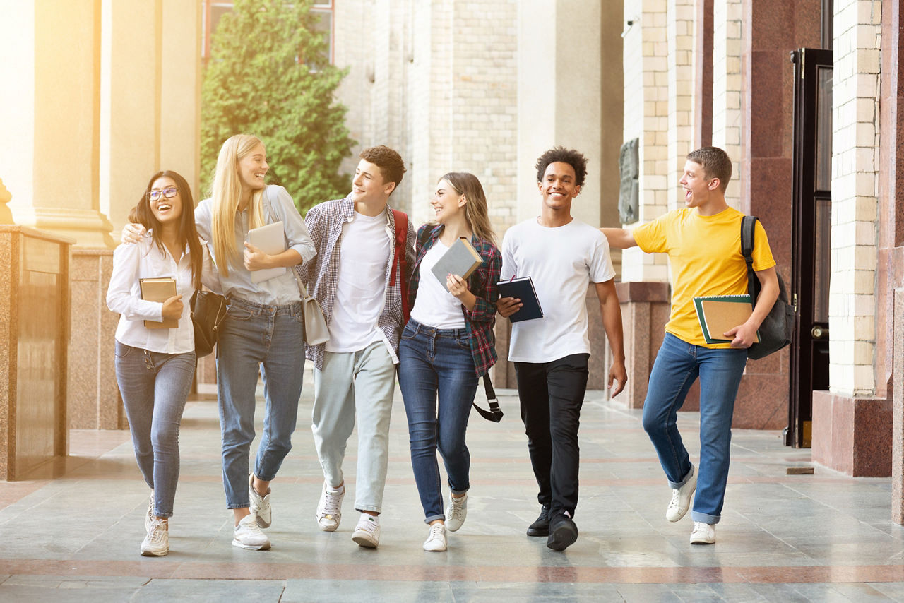 Gruppe junger Menschen verlässt glücklich die Universität oder Schule