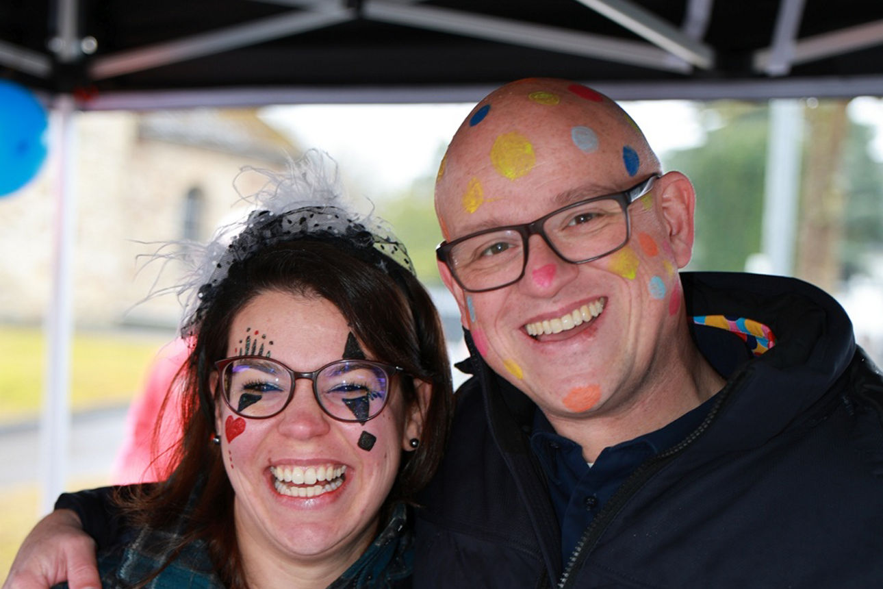 Stephanie Kröll und Dirk Asbeck lächeln fröhlich in die Kamera. Stephanie als Harlekin, Dirk als Konfetti verkleidet.