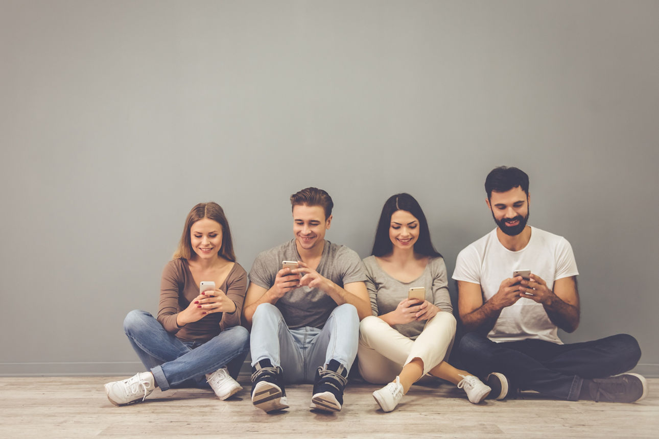 Junge Personen sitzen und spielen mit ihren Smartphones