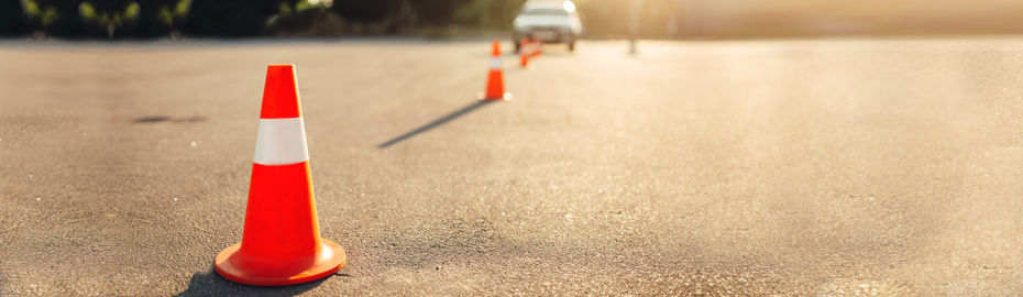 Eine Reihe von orangefarbenen Verkehrskegeln entlang der Straße, die einen Bau- oder Umleitungsbereich kennzeichnen.