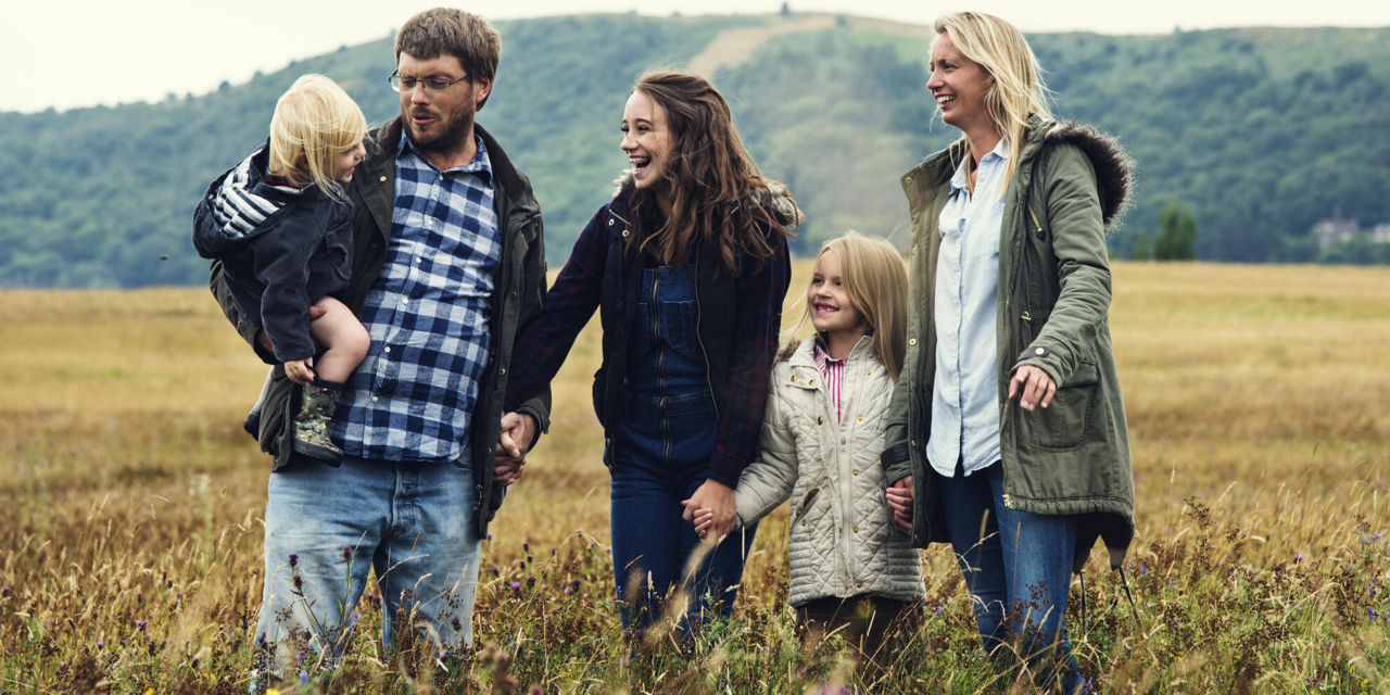 Eine Familie steht zusammen auf einem Feld. Alle schauen auf den jüngsten.