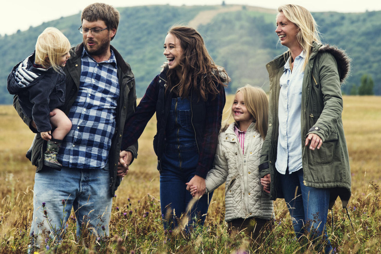 Eine Familie steht zusammen auf einem Feld. Alle schauen auf den jüngsten.