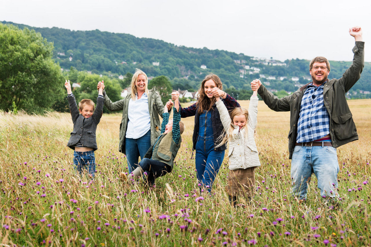 Eine Familie hält sich an den Händen und spaziert über ein Feld
