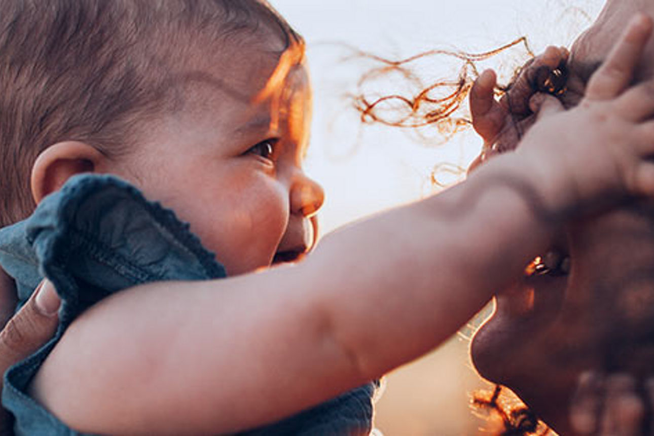 Eine Frau hält ihr Baby vor sich.