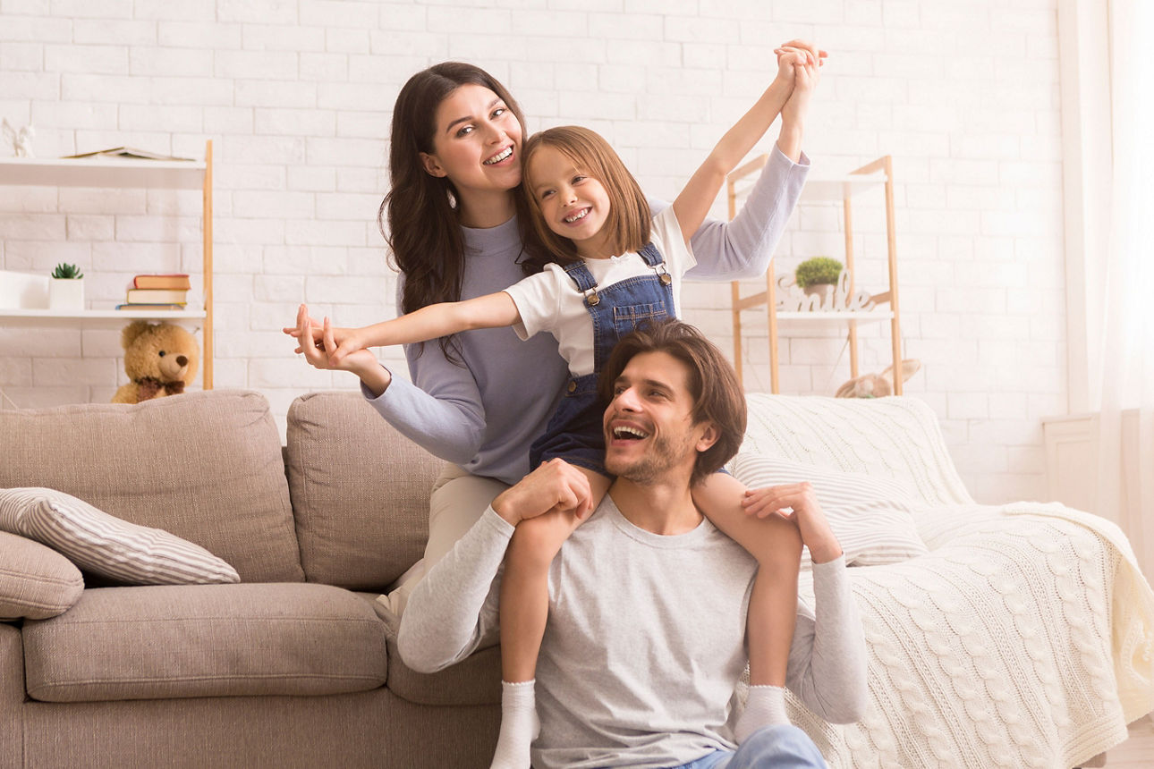 Fröhliche junge dreiköpfige Familie, die zu Hause zusammen albert und Spaß hat