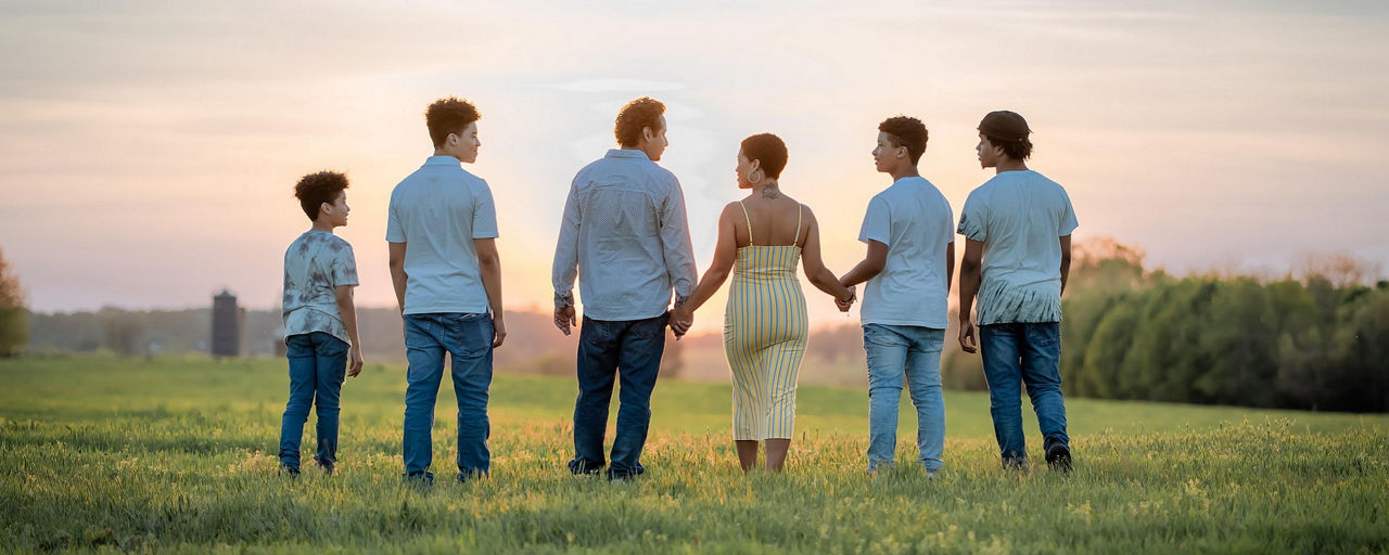 Eine Familie beobachtet den Sonnenuntergang auf einem Feld