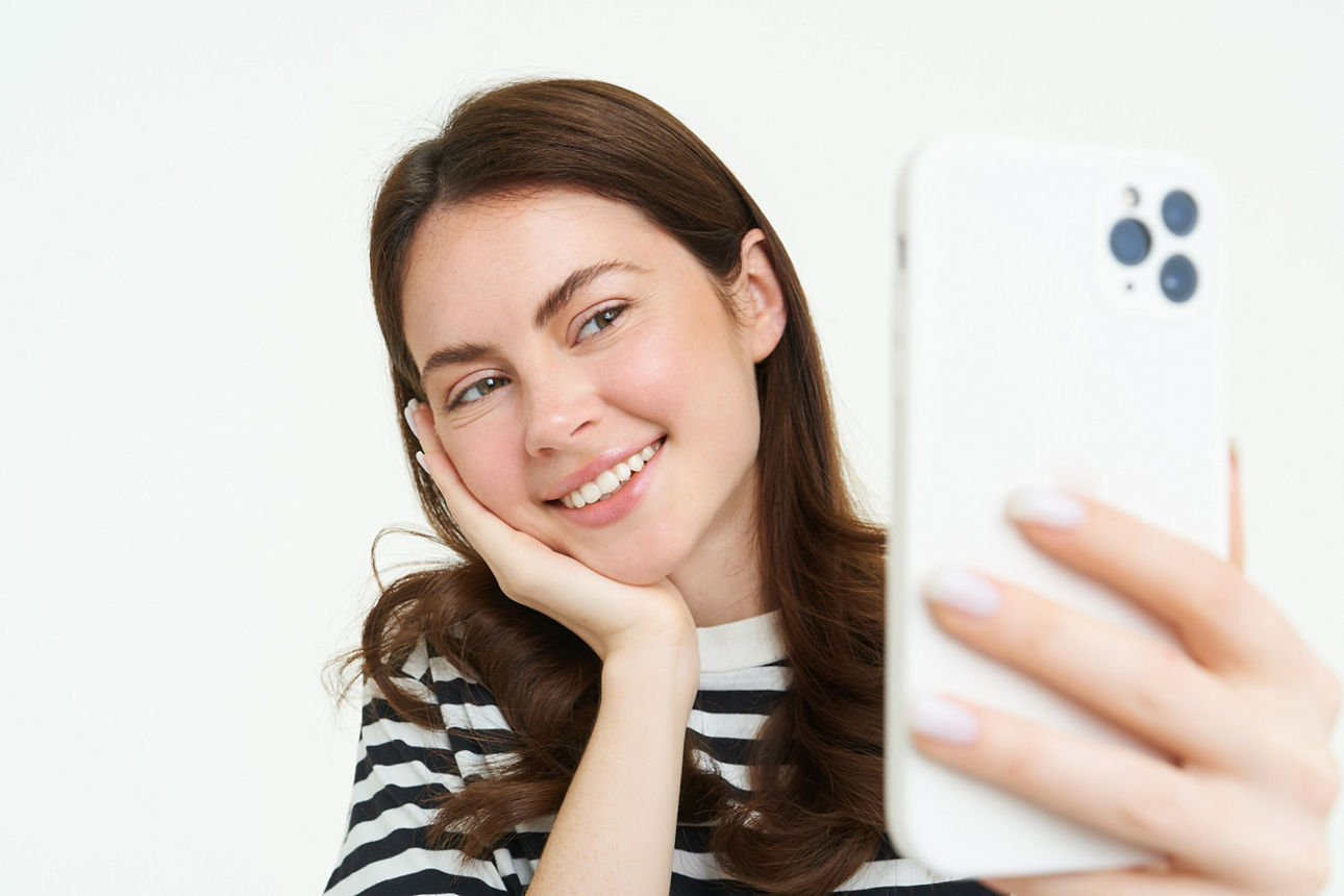 Junge Frau blickt erfreut auf Ihr  Handy