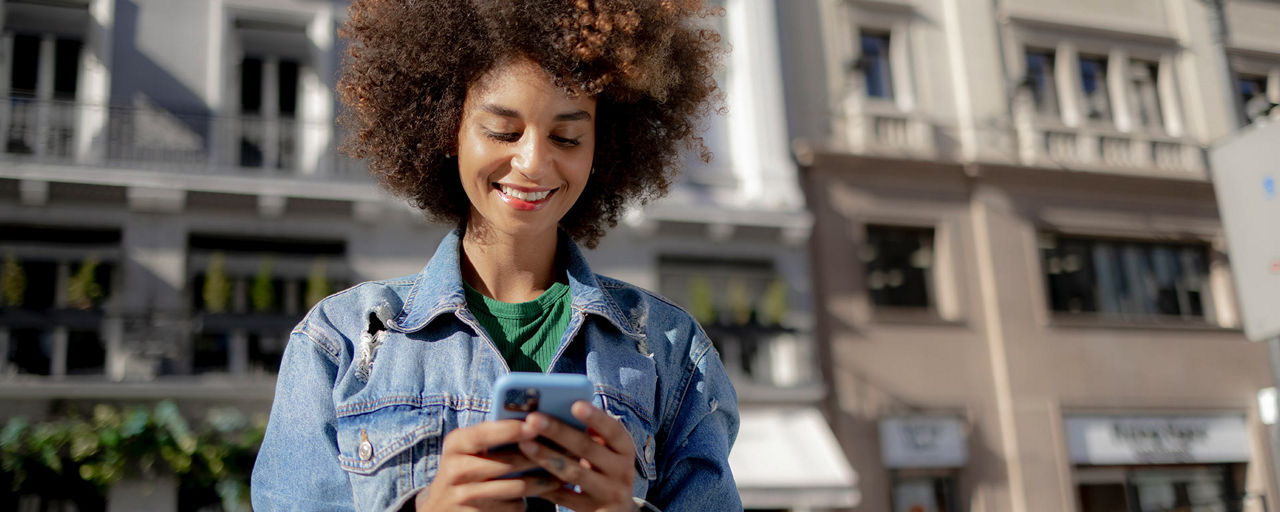Eine junge Frau schaut draußen auf ihr Handy
