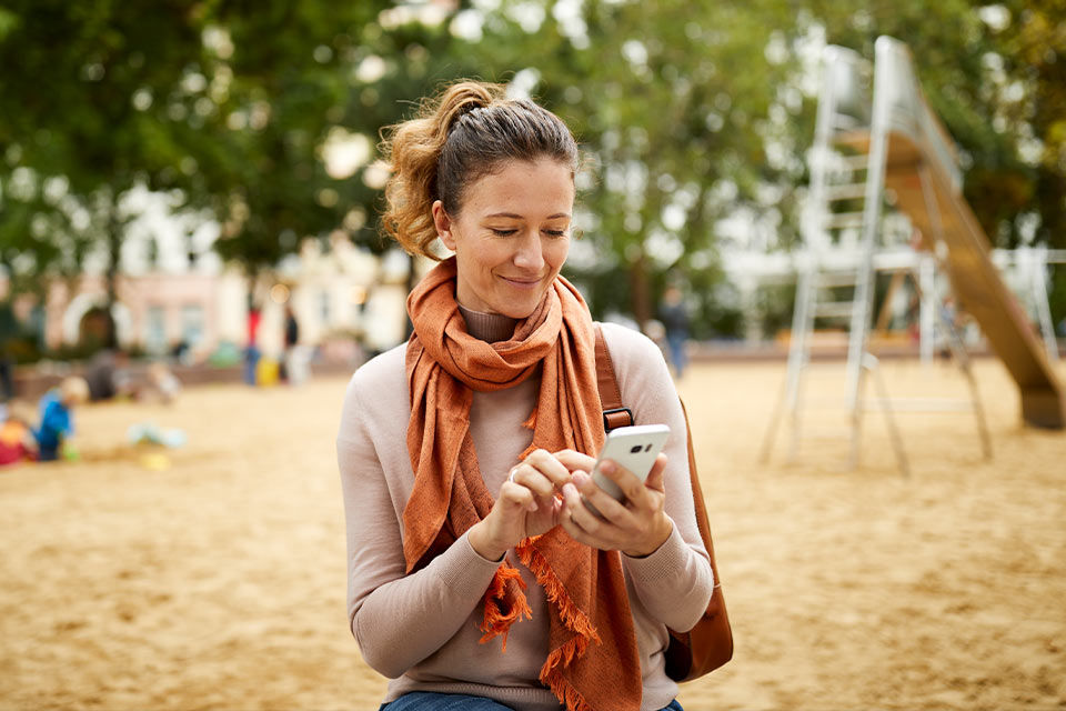 Fraz mit ihrem Handy in der Hand auf dem Spielplatz
