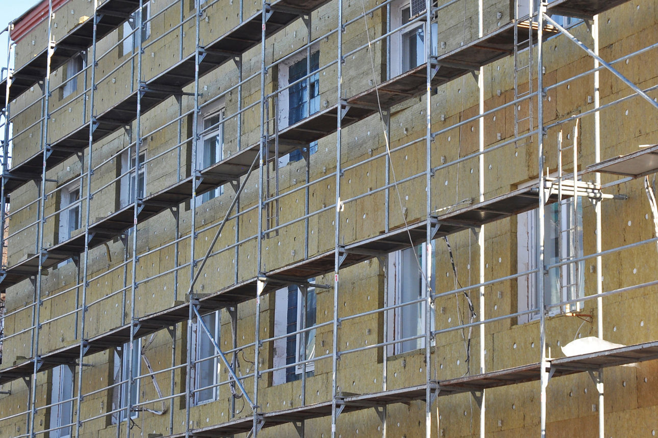 Energy efficiency office wall renovation for energy saving. Exterior house wall heat insulation with mineral wool, building hospital under construction.