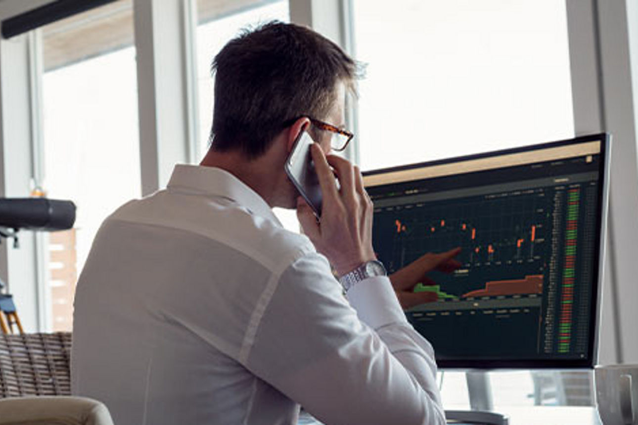 Ein Mann schaut auf einen Computerbildschirm und telefoniert