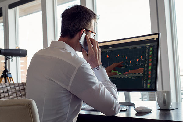 Ein Mann schaut auf einen Computerbildschirm und telefoniert