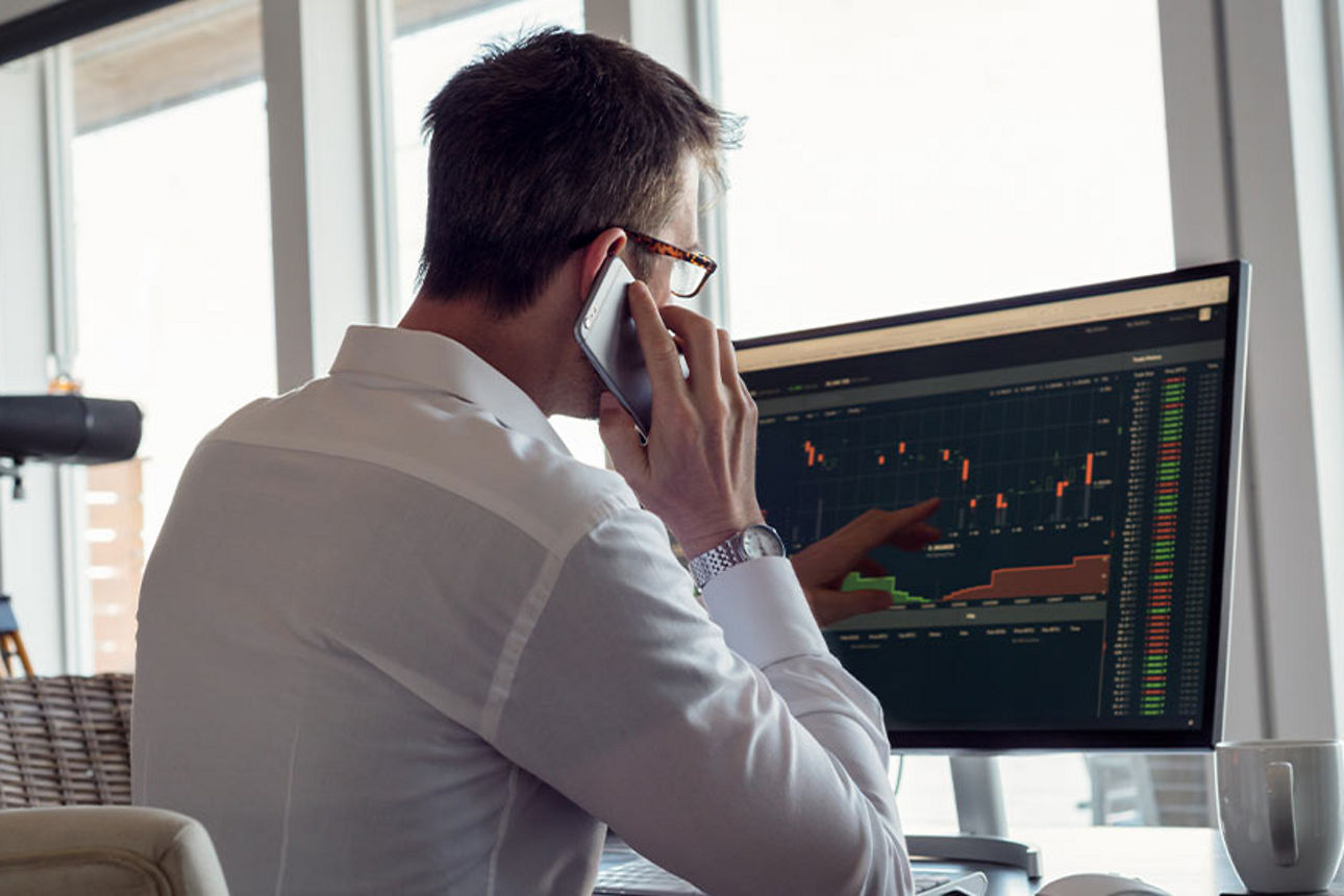 Ein Mann schaut auf seinen Computerbildschirm und telefoniert
