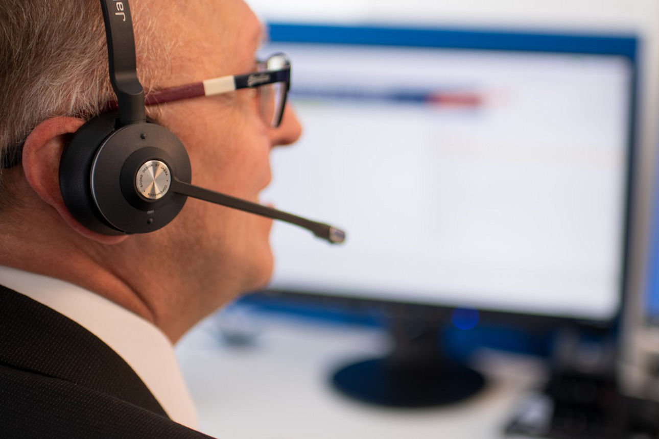 Mitarbeiter mit Headset schaut auf zwei Bildschirme