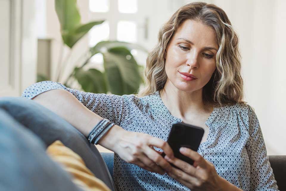 Eine Frau schaut entspannt auf ihr Smartphone