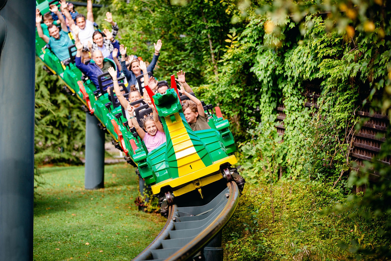 Einige Kinder sitzten in einer Achterbahn, die wie ein Drache ausschaut
