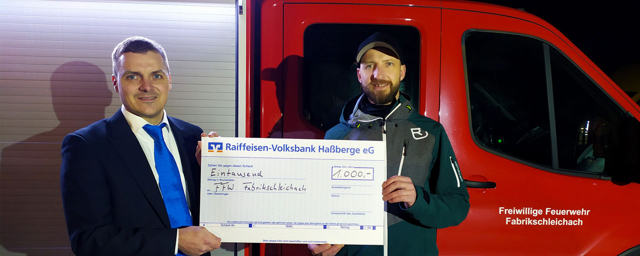 Firmenkundenberater Markus Simon übergibt einen Spendenscheck an den Feuerwehrverein Fabrikschleich